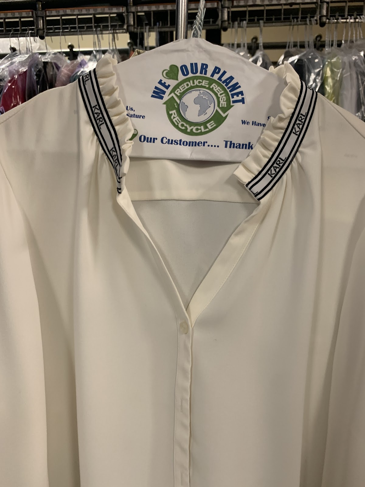 A freshly cleaned blouse on a hanger with eco-friendly garment-care branding at Twins Cleaners